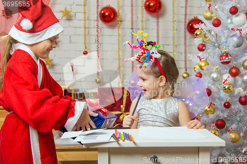 Image of Girl sits at a table with fireworks on the head, Santa Claus gave her a gift