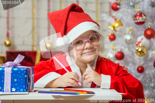 Image of Girl dressed as Santa Claus with glasses and drawing card for Christmas