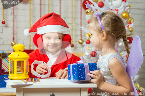 Image of Santa Claus and fairy fun to look at each other\'s assistant preparing greeting cards and gifts