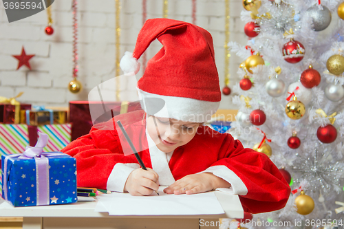 Image of Girl dressed as Santa Claus writing a list of desired gifts for Christmas