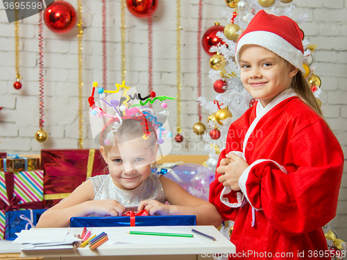 Image of Girl sits at a table with fireworks on the head with a gift that is presented to Father Christmas