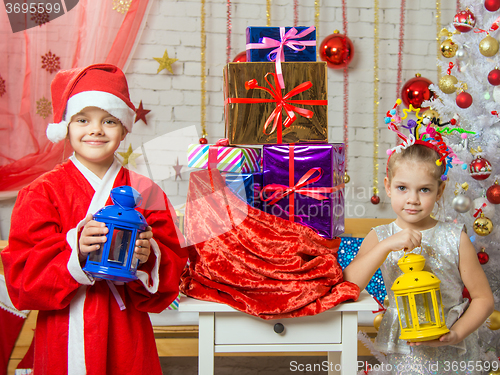 Image of Two girls in Christmas costumes are with candlesticks from the bag with Christmas gifts