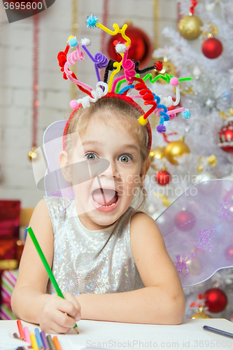 Image of Girl with a toy fireworks on the head draws a congratulatory New Years card