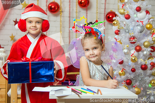 Image of Girl sits at a table with fireworks on the head, Santa Claus is a little behind with a gift