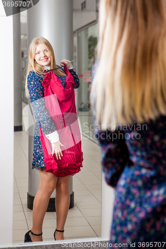 Image of Woman trying red dress shopping for clothing. 