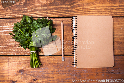 Image of Blank notebook and pencil with a bunch of herbs on wooden table