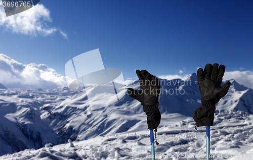 Image of Gloves on ski poles and snowy mountain 