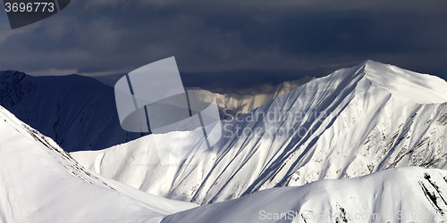 Image of Panoramic view on snowy sunlit mountains and overcast sky