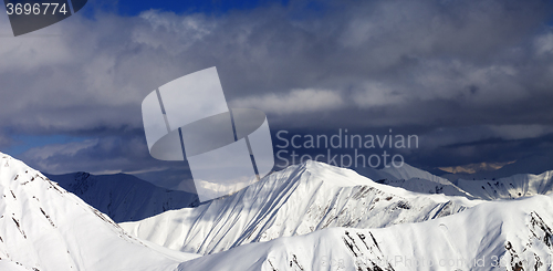 Image of Panoramic view on snowy sunlit mountains and cloudy sky
