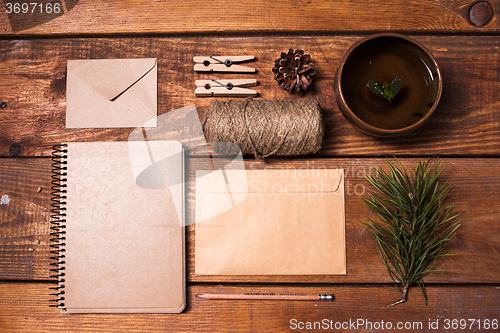 Image of Notebook for recipes, paper envelopess, rope and clothespins on wooden table.