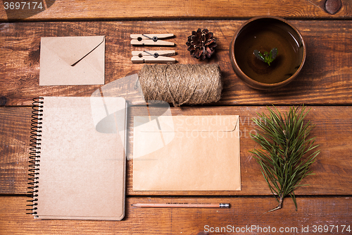Image of Notebook for recipes, paper envelopess, rope and clothespins on wooden table.