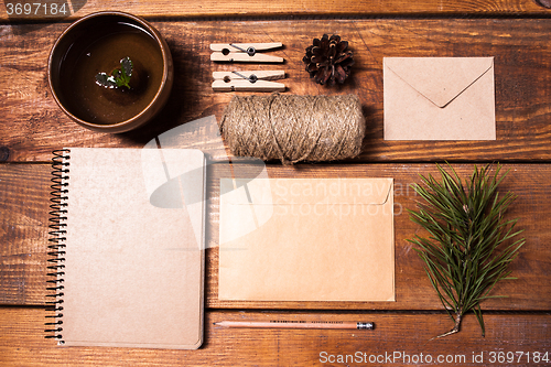 Image of Notebook for recipes, paper envelopess, rope and clothespins on wooden table.