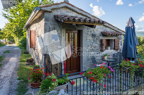 Image of small stone house with a metal fence