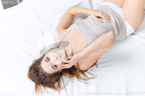 Image of The young girl in bed with phone