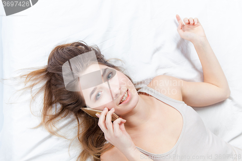 Image of The young girl in bed with phone