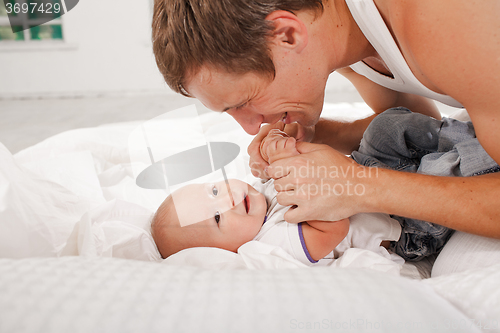 Image of young father with his nine months old son on the bed at home