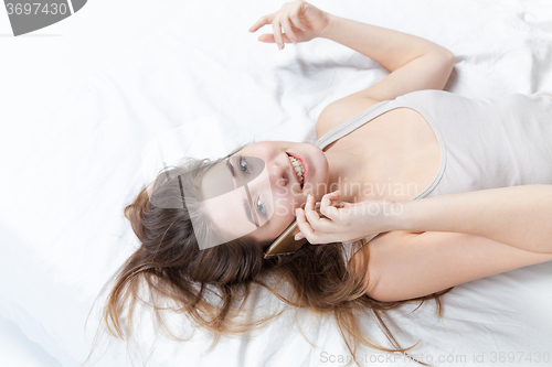 Image of The young girl in bed with phone