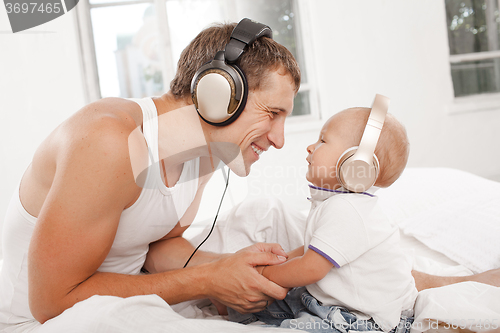 Image of young father with his nine months old som on the bed at home