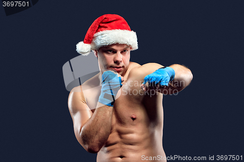 Image of Christmas fitness boxer wearing santa hat boxing on black 