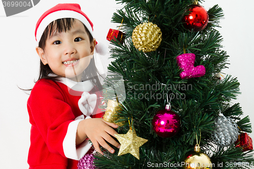 Image of Asian Chinese little girl posing with Christmas Tree