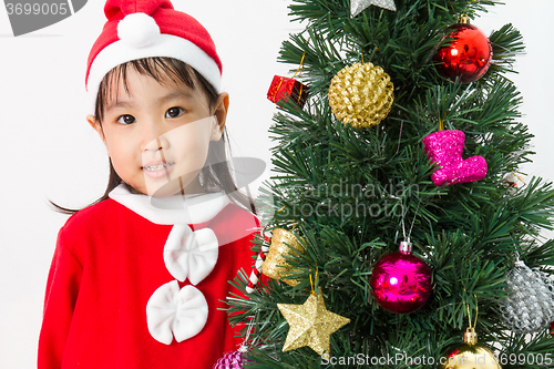 Image of Asian Chinese little girl posing with Christmas Tree