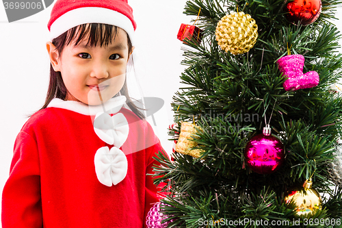 Image of Asian Chinese little girl posing with Christmas Tree