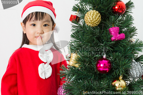 Image of Asian Chinese little girl posing with Christmas Tree