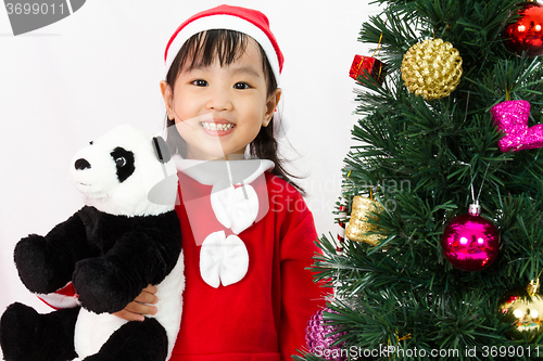 Image of Asian Chinese little girl holding panda doll posing with Christm