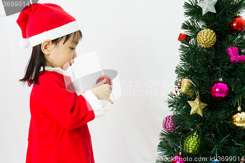 Image of Asian Chinese little girl posing with Christmas Tree