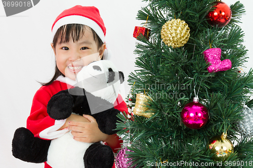 Image of Asian Chinese little girl holding panda doll posing with Christm