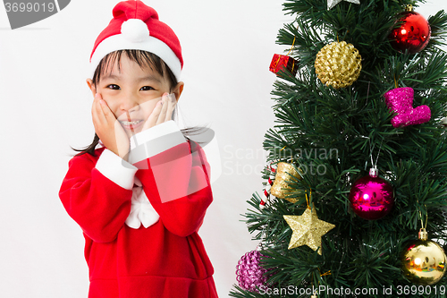 Image of Asian Chinese little girl posing with Christmas Tree