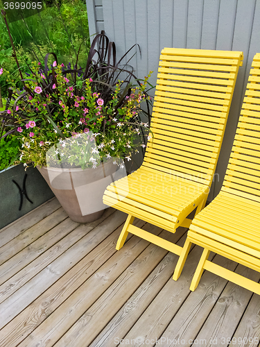 Image of House exterior decorated with yellow chairs and flowers