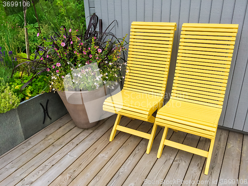 Image of Yellow chairs and flowers decorating house exterior