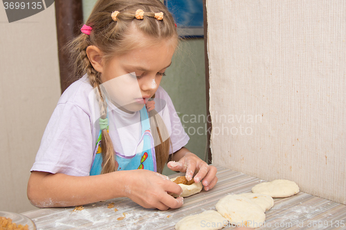 Image of Six year old girl concentrating sculpts cakes with cabbage