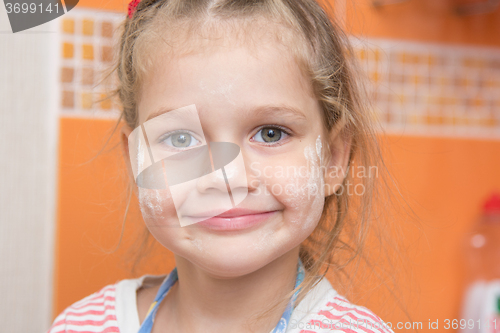 Image of Portrait of a cheerful girl with a face stained with flour