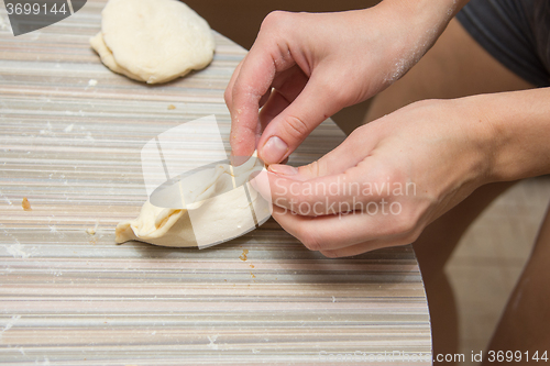 Image of Female hands fasten the seam pie on the kitchen table