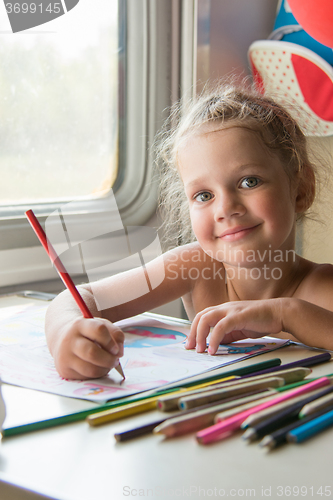 Image of Four-year girl draws pencil drawing of a table in a second-class train carriage