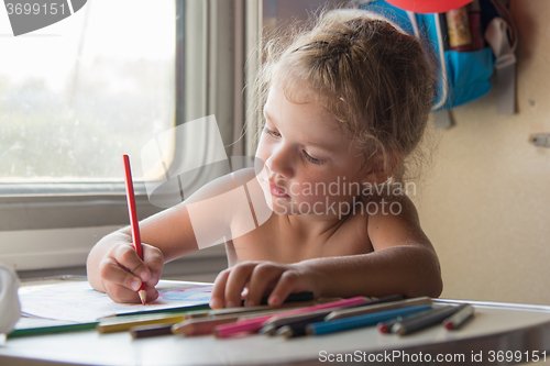 Image of Carried away by the girl draws pencils at the table in a train