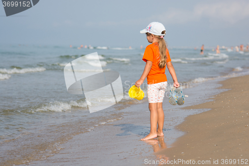 Image of Girl standing on the beach with a bucket and slaps hands