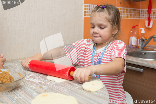 Image of Girl hard rolls rolling pin pancake dough for pies