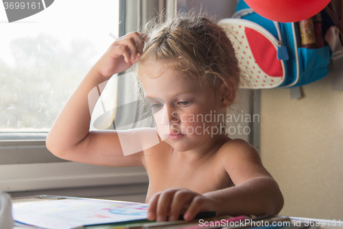 Image of Carried away by the girl thought drawing pencils at a table in a train