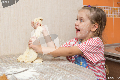 Image of Cheerful girl tears off a piece of dough