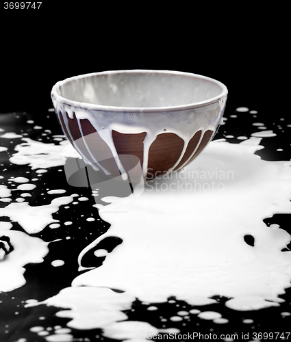 Image of Ceramic bowl and spilled milk in black