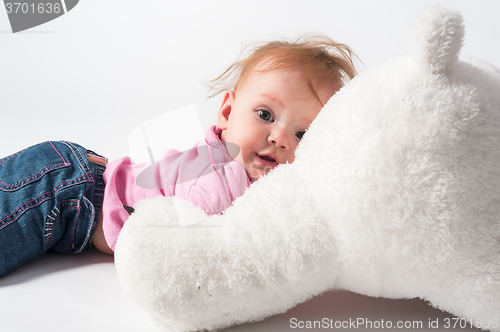 Image of Baby girl plays with white bear toy