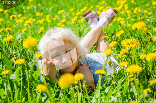 Image of A woman lies in a clearing and sniffs a flower  