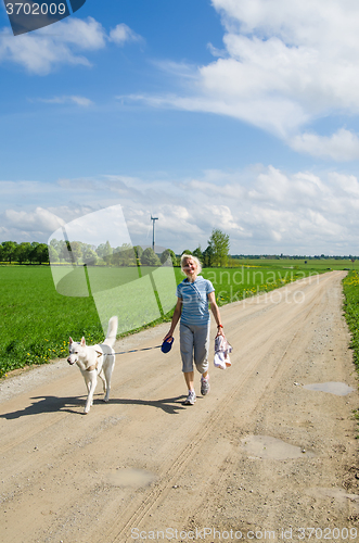 Image of Woman with a dog goes on a country road  
