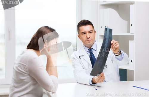 Image of smiling male doctor in white coat looking at x-ray