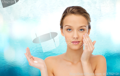 Image of young woman applying cream to her face