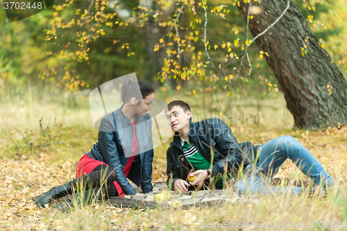 Image of Young romantic couple sits on plaid. Autumn picnic
