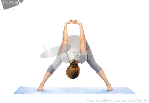 Image of woman making yoga wide-legged forward bend on mat